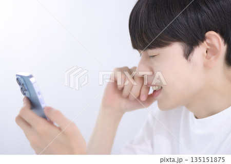 リビングでスマホを見て落胆する若い男性 リビングでスマホを見て落胆する若い男性 135151875