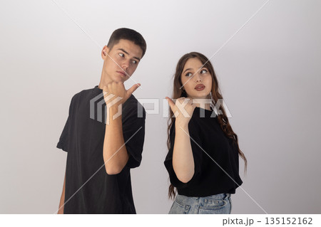 Two teenagers in black t-shirts making shush gestures. 135152162