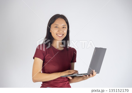 Happy woman holding a laptop and smiling at camera. 135152170