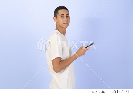 Man in a white shirt looking at his smartphone. 135152171