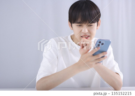 リビングでスマホを見て落胆する若い男性 リビングでスマホを見て落胆する若い男性 135152215