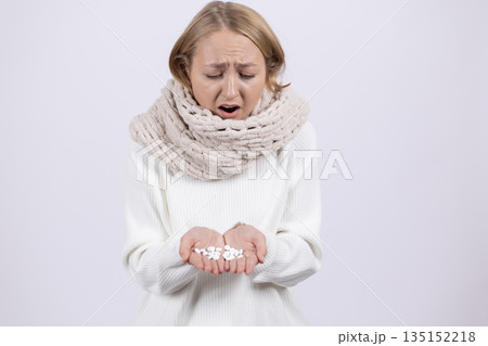 Sick woman looking at pills in her open palms. 135152218