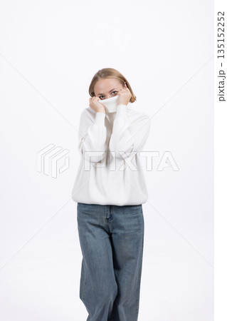 Scared woman covering her face with a white scarf. Scared woman covering her face with a white scarf. 135152252