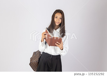 Teenager girl holding a notebook and looking thoughtful. 135152292