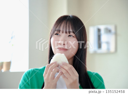 おにぎりを美味しそうに食べる若い女性 135152458