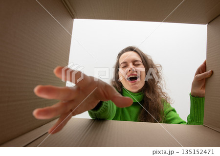 Woman taking a present from the bottom of the box with closed eyes Woman taking a present from the bottom of the box with closed eyes 135152471