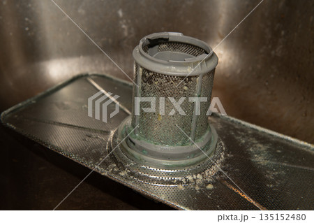 Dirty dishwasher filter showing mold and food debris requiring cleaning maintenance 135152480