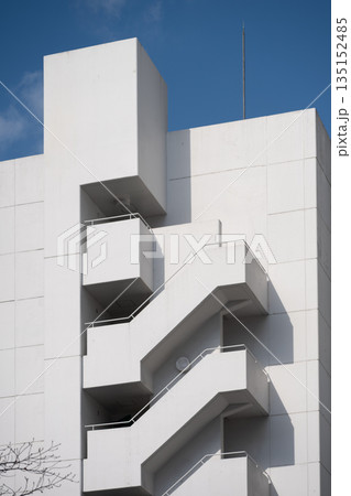White fire escape stairs climbing a modern building White fire escape stairs climbing a modern building 135152485