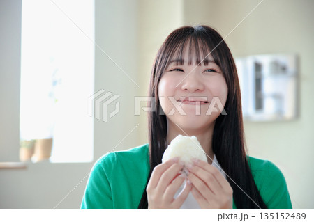 おにぎりを美味しそうに食べる若い女性 135152489
