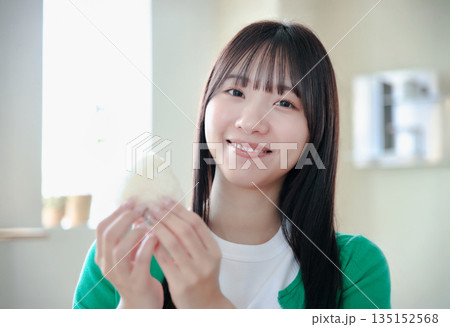 おにぎりを美味しそうに食べる若い女性 135152568