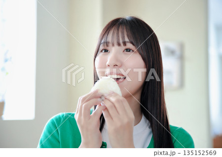 おにぎりを美味しそうに食べる若い女性 135152569