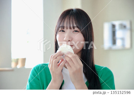 おにぎりを美味しそうに食べる若い女性 おにぎりを美味しそうに食べる若い女性 135152596