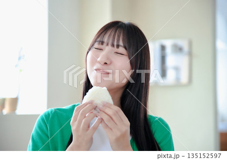 おにぎりを美味しそうに食べる若い女性 135152597
