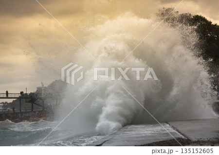 Autumn storm on sea, breaking huge waves near embankment. Stormy sea Autumn storm on sea, breaking huge waves near embankment. Stormy sea 135152605