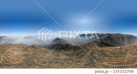A panoramic shot of a mountain range with a cloudy sky in the background 135152709