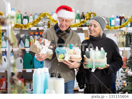 Senior spouses studies label and choose shower cosmetic present, packaged in basket on Christmas Eve 135155604