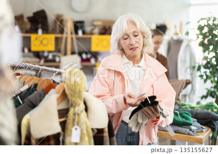Mature woman choosing gloves in the store Mature woman choosing gloves in the store 135155627