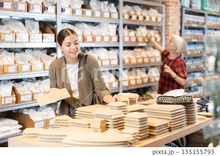 Woman chooses various wooden molds for future clay molding in her workshop 135155793