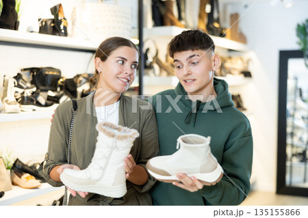Couple man and woman choosing winter boots in store 135155866