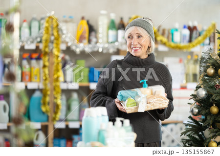 Elderly woman buyer chooses cosmetics gift set for christmas 135155867
