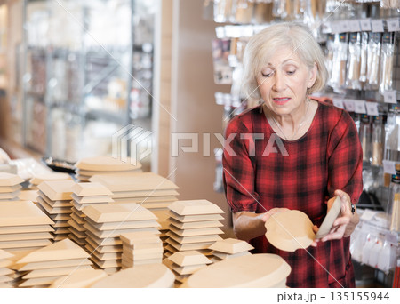 Elderly female customer chooses various wooden molds for future clay molding 135155944