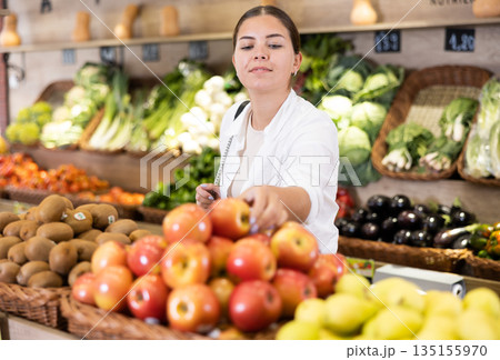 Delighted young woman purchaser choosing apples in grocery store 135155970