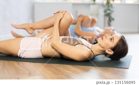 Young woman doing yoga in group in studio Young woman doing yoga in group in studio 135156095