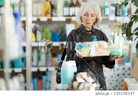Elderly woman chooses gift set of shampoo, liquid soap and cosmetic items in supermarket Elderly woman chooses gift set of shampoo, liquid soap and cosmetic items in supermarket 135156147