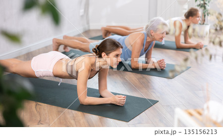 Women of different generations yoga showing plank pose in wellness center Women of different generations yoga showing plank pose in wellness center 135156213