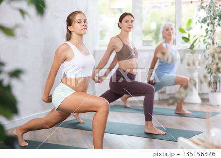 Young and mature women training yoga positions in yoga studio Young and mature women training yoga positions in yoga studio 135156326
