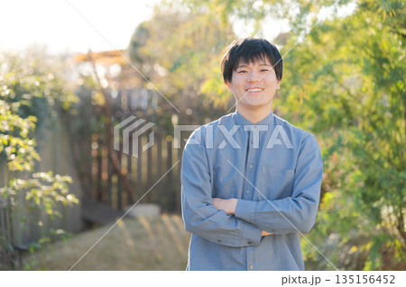 家の庭で腕を組んで立つ男性 135156452