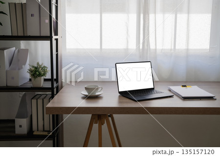 Minimal home office desk with laptop and natural window light, clean background for business website headers, presentations, and ads with generous copy space. Minimal home office desk with laptop and natural window light, clean background for business website headers, presentations, and ads with generous copy space. 135157120