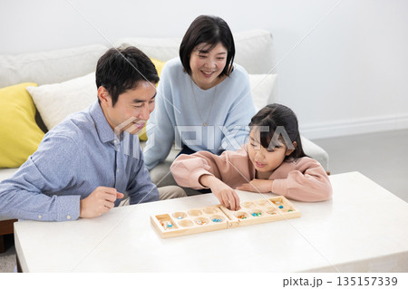 自宅のリビングでマンカラを楽しむ親子 135157339