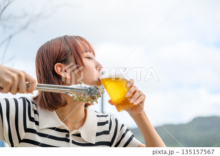 屋外でビールと海鮮を楽しむ女性 【撮影協力：隠岐シーサイドリゾートみやび様】 135157567