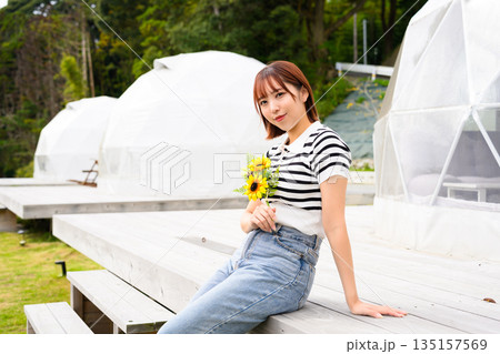 グランピング場でひまわりを持つ女性 【撮影協力：隠岐シーサイドリゾートみやび様】 135157569