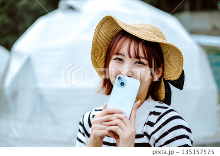 麦わら帽子とスマホを持つ女性 【撮影協力：隠岐シーサイドリゾートみやび様】 135157575