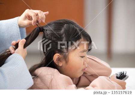 自宅のリビングで母親に髪をセットしてもらう小学生の女の子 135157619