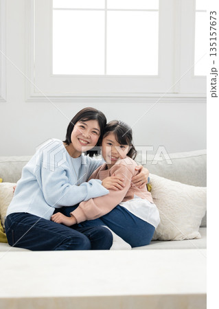 リビングのソファでふれあう母親と小学生の女の子 リビングのソファでふれあう母親と小学生の女の子 135157673