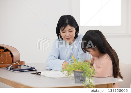 母親に勉強を教えてもらう小学生の女の子 135158006
