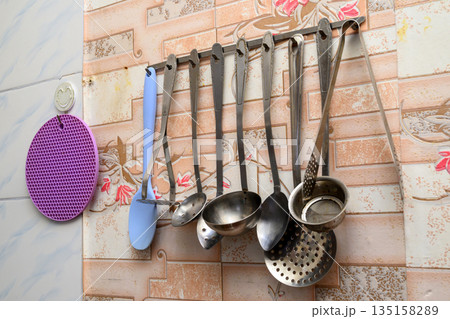 kitchen utensils and a purple trivet on the wall 135158289