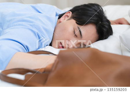 ベッドを寝落ちして朝を迎える若い男性 ベッドを寝落ちして朝を迎える若い男性 135159203