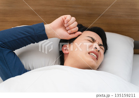 うなされながら眠る若い男性 ライフスタイルイメージ うなされながら眠る若い男性 ライフスタイルイメージ 135159211