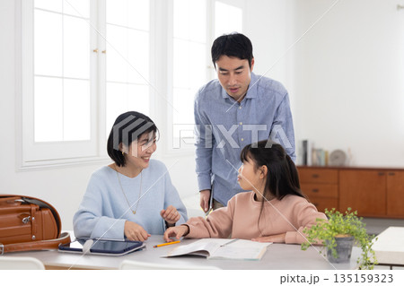 両親と一緒に自宅で学習を楽しむ小学生の女の子 両親と一緒に自宅で学習を楽しむ小学生の女の子 135159323