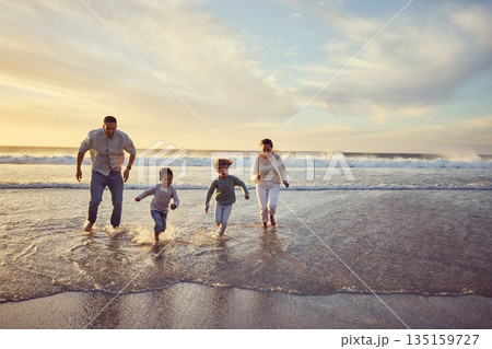Beach, sunset and parents run with children on holiday, summer vacation and weekend together. Nature, travel and happy mother, father and kids play in ocean for bonding, adventure and family time 135159727