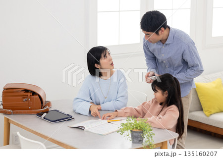 自宅で子供に勉強を教えながら困った表情をする両親 自宅で子供に勉強を教えながら困った表情をする両親 135160207