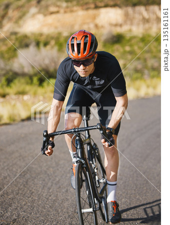 Exercise, bike and cycling with a sports man on a road through the mountain for cardio or endurance. Fitness, workout or training with a male cyclist riding his bicycle on an asphalt street in nature 135161161