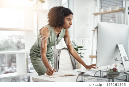 Computer, planner and business woman writing in a notebook or working by her desk or table in startup. Internet, online and professional female employee or worker planning company schedule 135161366