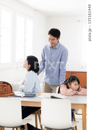 自宅学習中に険しい表情で顔を背ける母娘と困惑する父親 自宅学習中に険しい表情で顔を背ける母娘と困惑する父親 135161449