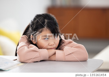 憂鬱な表情でテーブルに伏せる小学生の女の子 憂鬱な表情でテーブルに伏せる小学生の女の子 135161454