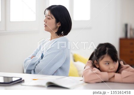 自宅学習中に険しい表情で顔を背ける母親と小学生の子供 135161458